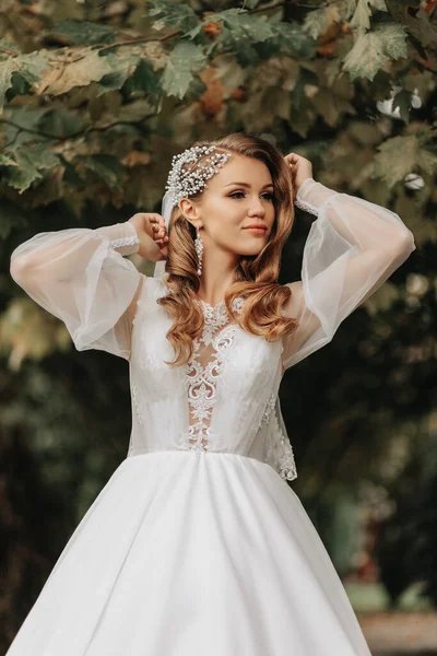 スリーブ付きのウェディングドレスの花嫁の写真 美しい髪型と彼女の頭にティアラ 彼女の手の花束と — ストック写真