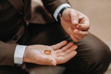 Bir adamın elinde altın alyanslar. Düğün konsepti