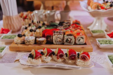 Düğün kutlamalarında farklı lezzetli yemeklerden oluşan büyük bir açık büfe. Misafirler için atıştırmalıklar. Düğün partisi. Kanepeler, suşi, meyve, et, içecek, şarap, meyve suyu.