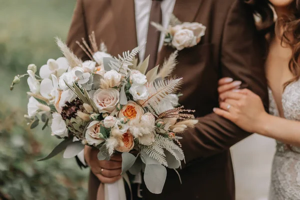 花嫁の手で結婚式の花束をクローズアップし 自然の中で成長する — ストック写真
