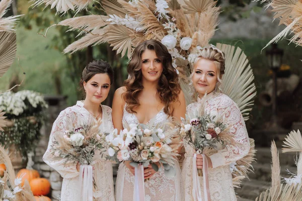 결혼식 아치의 배경에 동일한 꽃다발을 신부와 그녀의 친구의 — 스톡 사진