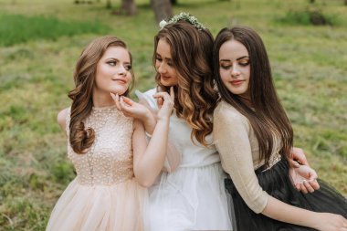 Ormanda düğün yürüyüşü. Gelinler ve arkadaşları ormanın arka planında poz veriyorlar. Büyük bir grup insan arkadaşlarının düğününde eğleniyor.