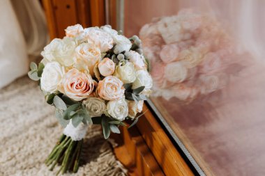 Pencerenin yanında bir buket pembe ve beyaz gül.