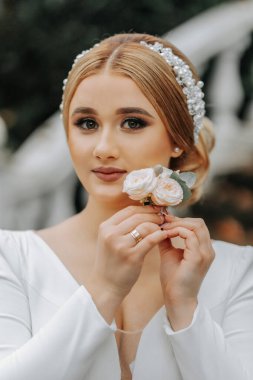 Gelinin ellerinde bir gül yaka çiçeğinin portresi, kızın yüzüne yakın büyüdü.