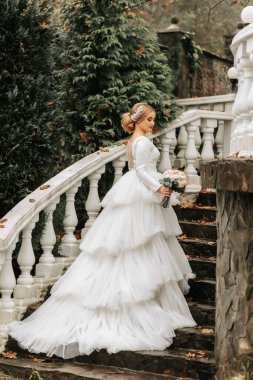 Gelinlik giymiş bir gelinin portresi ve zarif adımlarla giden bir tren. Tam boy fotoğraf. Düğün en iyi yerde.