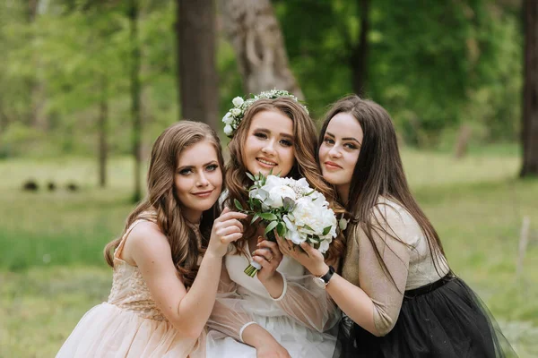 Wedding walk in the forest. Brides and their friends pose against the background of the forest. A large group of people are having fun at their friends\' wedding