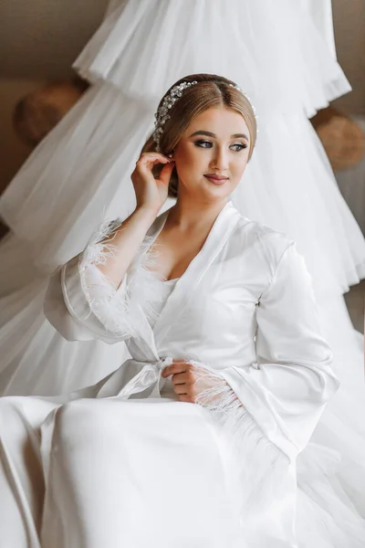 portrait of a beautiful bride in a hotel near a wedding dress. Preparation for the wedding ceremony. Vertical photo.