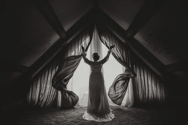 ウェディングドレスの花嫁はカーテンを開け 彼女の手を広げる — ストック写真
