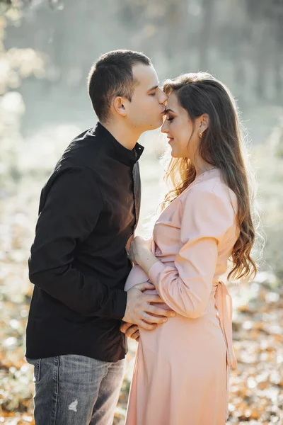 日落时 一个男人和他怀孕的妻子在森林里拥抱和亲吻 快乐的家庭观念 — 图库照片