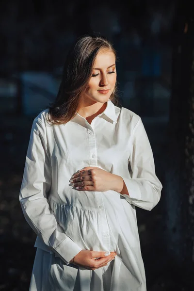 Uma Mulher Grávida Vestido Branco Fundo Escuro Posa Parque Gravidez — Fotografia de Stock