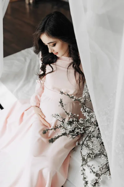 Красивая Беременная Женщина Длинными Темными Волосами Розовом Платье Касаясь Живота — стоковое фото