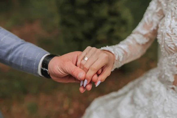 the bride and groom are tenderly holding hands close-up