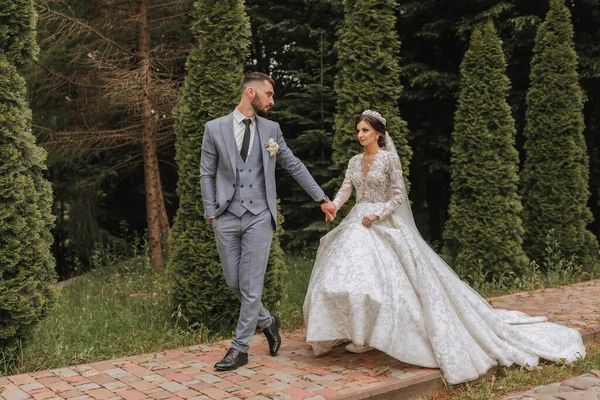 Европейская Свадебная Пара Прогуливается Парку Невеста Красивом Платье Рукавами Короной — стоковое фото