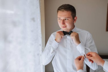 Arkadaşlar damadın papyonunu bağlayıp düğüne hazırlanmasına yardım edin.