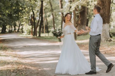 Bir yaz parkında yürüyen genç bir çift yeni evli. Kafasında taze çiçek çelengi olan beyaz elbiseli gelin, beyaz gömlekli damat.
