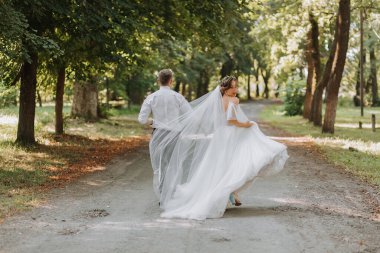 Bir düğün çifti, mutlu bir gelin ve damat düğün töreninin yapılacağı parka doğru koşuyorlar. Düğün konsepti