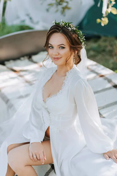 木の下の庭のベッドの花嫁の朝 花嫁は白いドレスと彼女の頭に新鮮な花のティアラを着ています — ストック写真