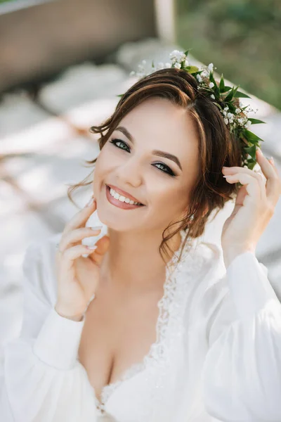 木の下の庭のベッドの笑顔の花嫁の肖像画 花嫁は白いドレスと彼女の頭に新鮮な花のティアラを着ています — ストック写真