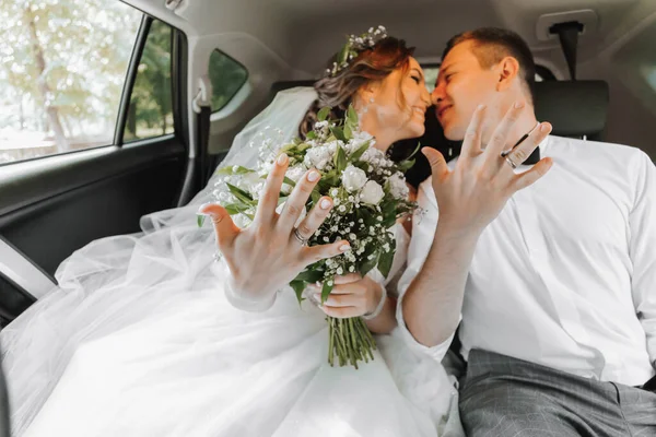 若い幸せな花嫁とグロムは彼らの車の結婚式の後に喜んでいる — ストック写真