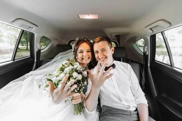 若い幸せな花嫁とグロムは彼らの車の結婚式の後に喜んでいる — ストック写真