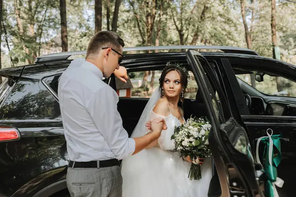 結婚式の肖像画 白いシャツと弓のネクタイと黒い車の近くの花束が付いているブルネットの花嫁のスタイリッシュな花の写真 — ストック写真