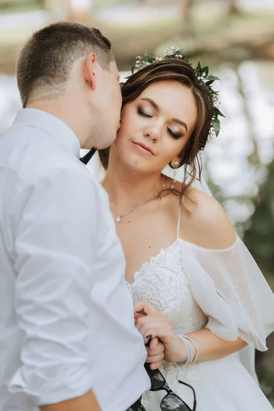 サマーパークの新婚旅行の肖像画 彼女の頭の上に新鮮な花の輪が付いている美しい白いドレスの花嫁 白いシャツの花嫁 — ストック写真
