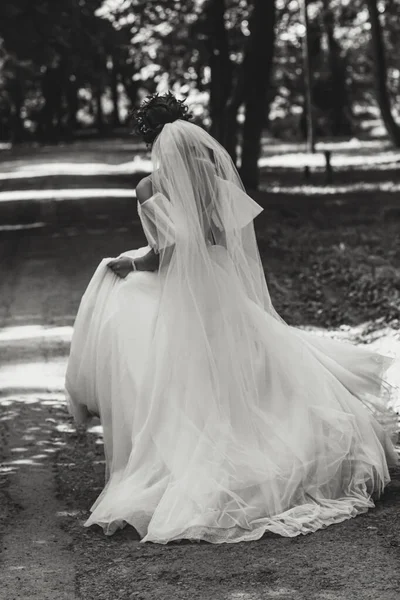 公園で長いベールのドレスで走っている幸せな花嫁 黒と白の写真 — ストック写真