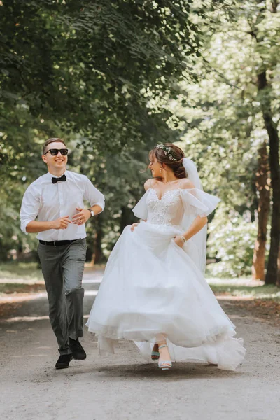 Een Bruidspaar Een Gelukkige Bruid Bruidegom Rennen Het Park Naar — Stockfoto