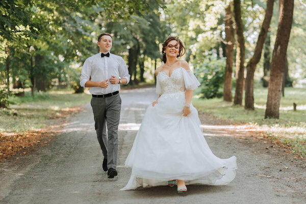 A wedding couple, a happy bride and groom are running in the park to the place of the wedding ceremony. Wedding concept