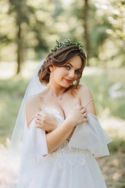 晴れた夏の日の森の緑の背景にポーズするエレガントな白いドレスで美しいかわいい花嫁の女の子の肖像画 — ストック写真