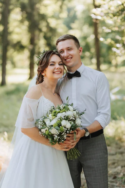 新鮮な花のティアラとファッショナブルなグルームとかわいい花嫁 公園で笑い 屋外の森 結婚式の写真 新婚旅行の笑顔の肖像画 — ストック写真