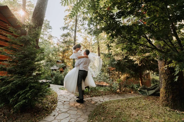 新鮮な花のティアラと屋外の公園 森で笑って白いドレスでファッショナブルなグルームとかわいい花嫁 結婚式の写真 新婚旅行の笑顔の肖像画 — ストック写真
