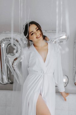 Kafasında duvak ve taç olan beyaz cüppeli, güzel bir gelin kız. Pencereden güneş ışıldıyor. Güneş ışığı altında mutlu genç bir kız. düğün kavramı