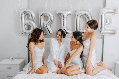 Gelinin odasındaki yatakta beyaz ipek elbiseli genç nedimeler. Bekarlığa veda partisini yatakta kutlayan güzel kadınlar..