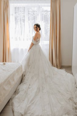 Odasında uzun bir tren olan şık elbiseli esmer gelin.