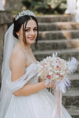 Gelinin ellerinde pembe güllerden, tüylerden ve kurumuş çiçeklerden oluşan bir buket
