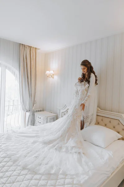 Beyaz Etekli Güzel Bir Gelin Bir Yatağın Üzerinde Duruyor Elinde — Stok fotoğraf