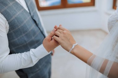 Gelin ve damadın el ele tutuşan portresi. Gelinlik giymiş güzel bir gelin, klasik takım elbiseli bir damat. Boş alan