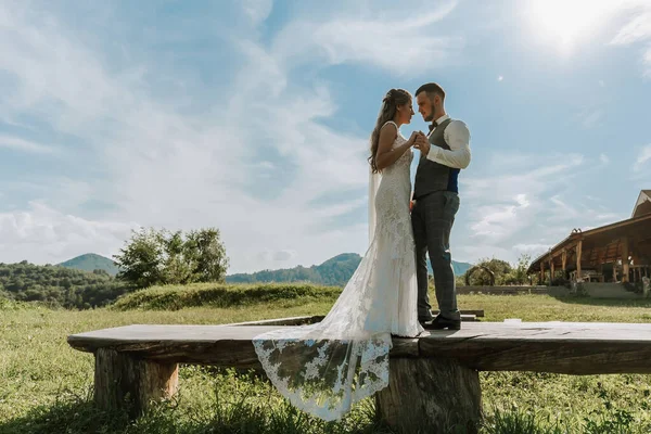 stylish bride and groom hug and kiss against the background of summer mountains. the concept of a rustic wedding in the mountains, happy bohemian newlyweds.