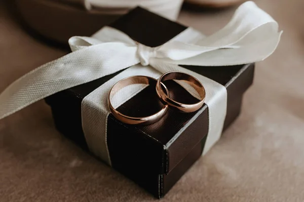 gold wedding rings on a brown box with a white ribbon