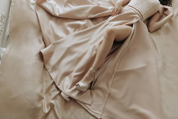 サテンファブリックで作られた夜のドレスでベッドに横たわる女性の写真 — ストック写真