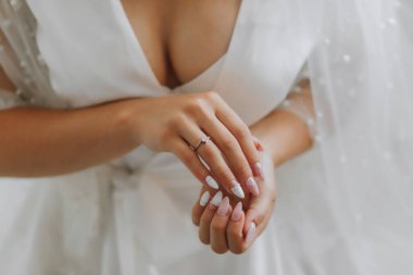 Gelinin elinde lüks altın bir alyans. Güzel eller ve manikür. Yaka açık. Kesilmiş fotoğraf