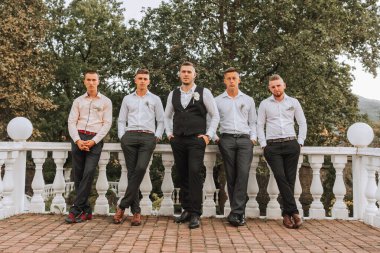 Neşeli, genç, enerjik damat tanıkları damadın yanında beyaz gömlekli. Arkadaşlar, damadı tebrik edin..