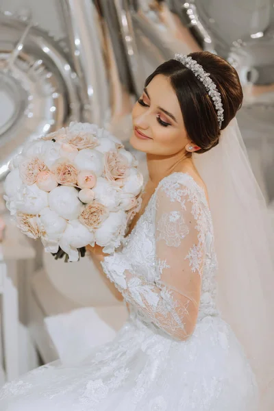 Красивая Молодая Невеста Свадебном Платье Букетом Пионов Руках Сидит Кровати — стоковое фото