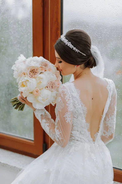 新鮮な白とピンクの花の美しい柔らかい花束を保持する白いドレスの非常に素敵な若い女性 — ストック写真