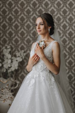 Gelin damat için beyaz bir yaka çiçeği tutuyor. Düğün aksesuarları