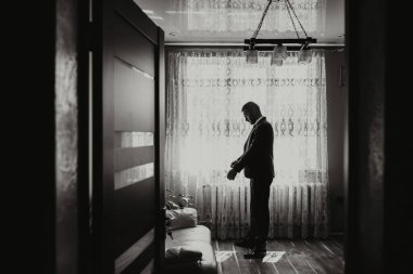 Damat odasında, pencerenin kenarında giyiniyor ve düğün töreni için hazırlanıyor.