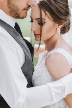 Güzel bir düğün, birbirine aşık güzel bir çift, yeşil bir bahçenin arka planında gülüp öpüşen. Yüksek kalite fotoğraf