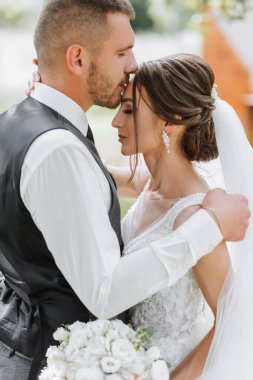 Güzel bir düğün, birbirine aşık güzel bir çift, yeşil bir bahçenin arka planında gülüp öpüşen. Yüksek kalite fotoğraf