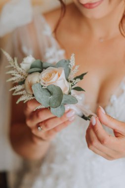 Gelin zarif bir elbise giymiş, elinde yaka çiçeğiyle. Düğün detayları. Bulanık arkaplan